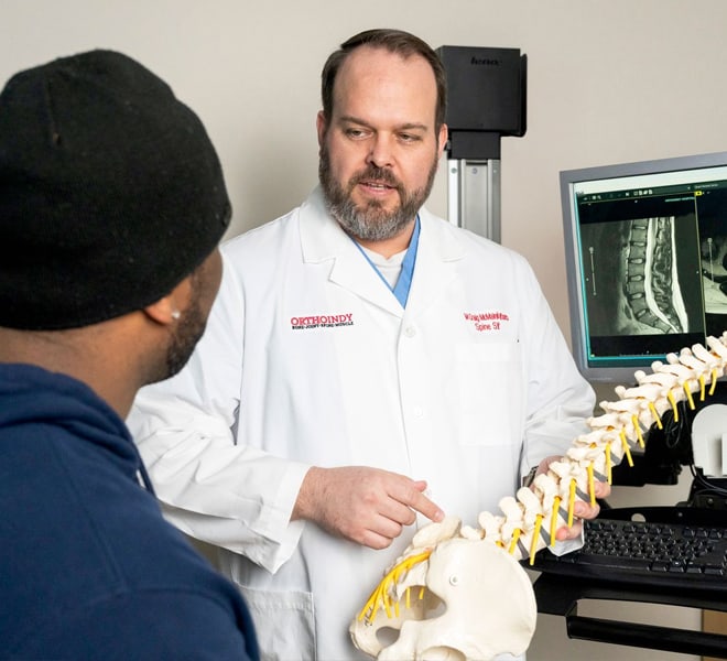 Dr. McMains holding a model of the spine to explain treatments to a patient